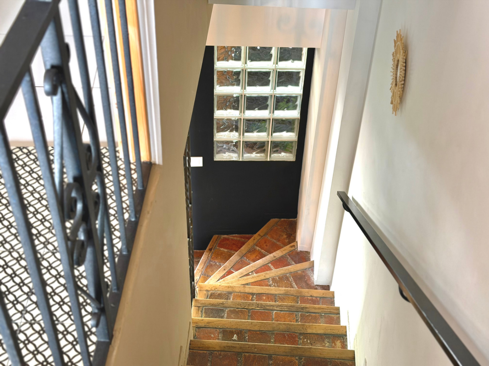 Interior staircase detail with brick steps and wrought iron railing.
