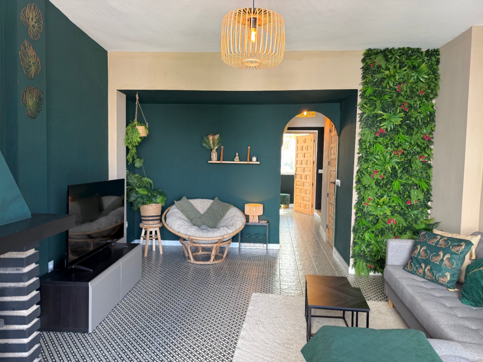 Living room featuring a vertical green wall, patterned tile flooring, and eclectic decor.