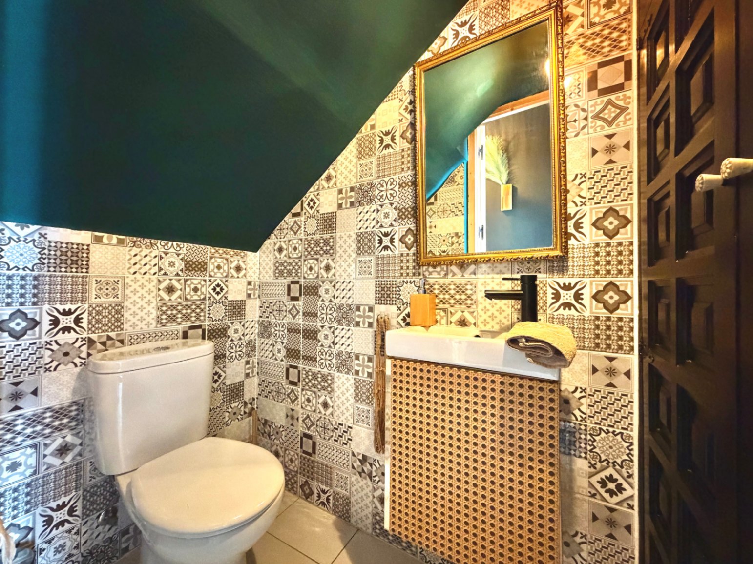 Powder room featuring patterned tile walls, a dark green ceiling, and a sink with a wicker mesh cabinet.