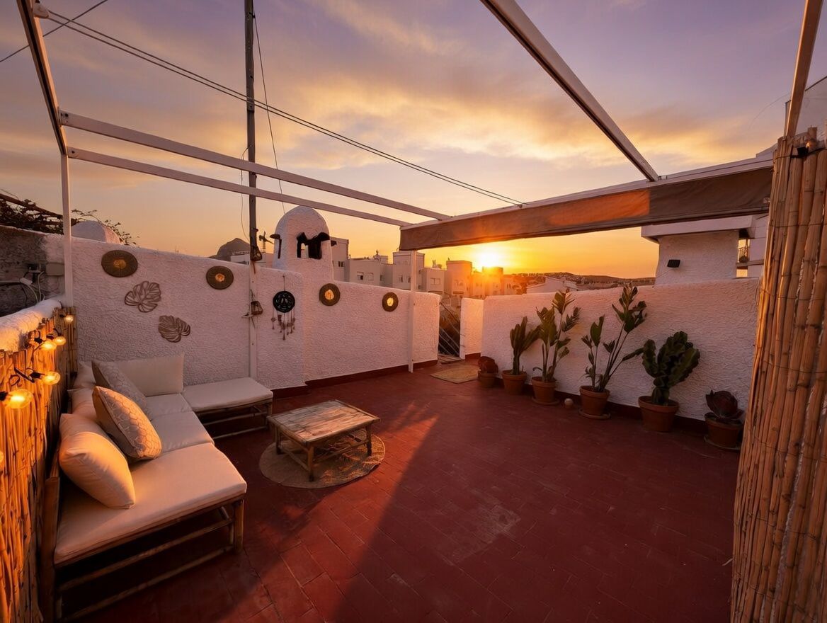 Private rooftop terrace with terracotta flooring, potted plants, bamboo furniture, and sunset views.