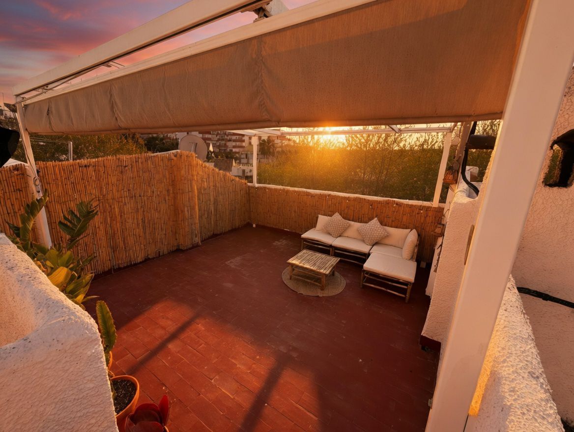 Private terrace with awning, red tile floor, and bamboo fence. Features a sectional sofa and coffee table.