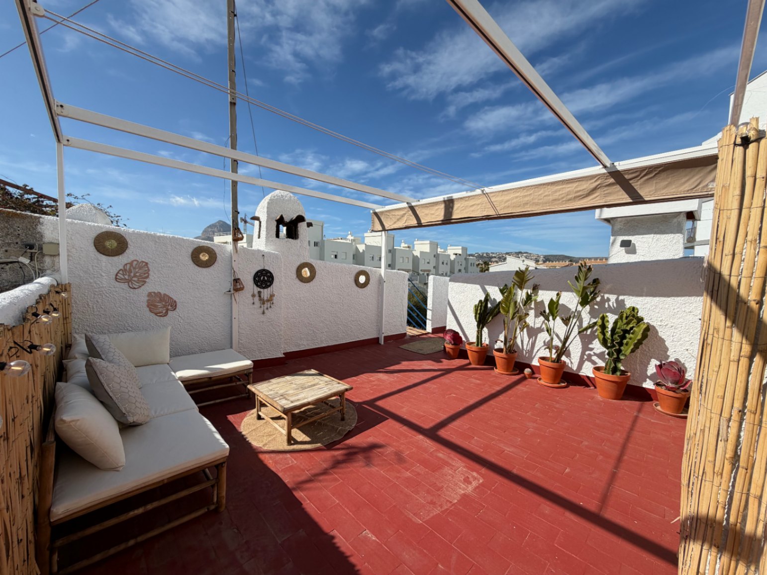Terrace with terracotta floor, bamboo furniture, and handcrafted wall decorations.