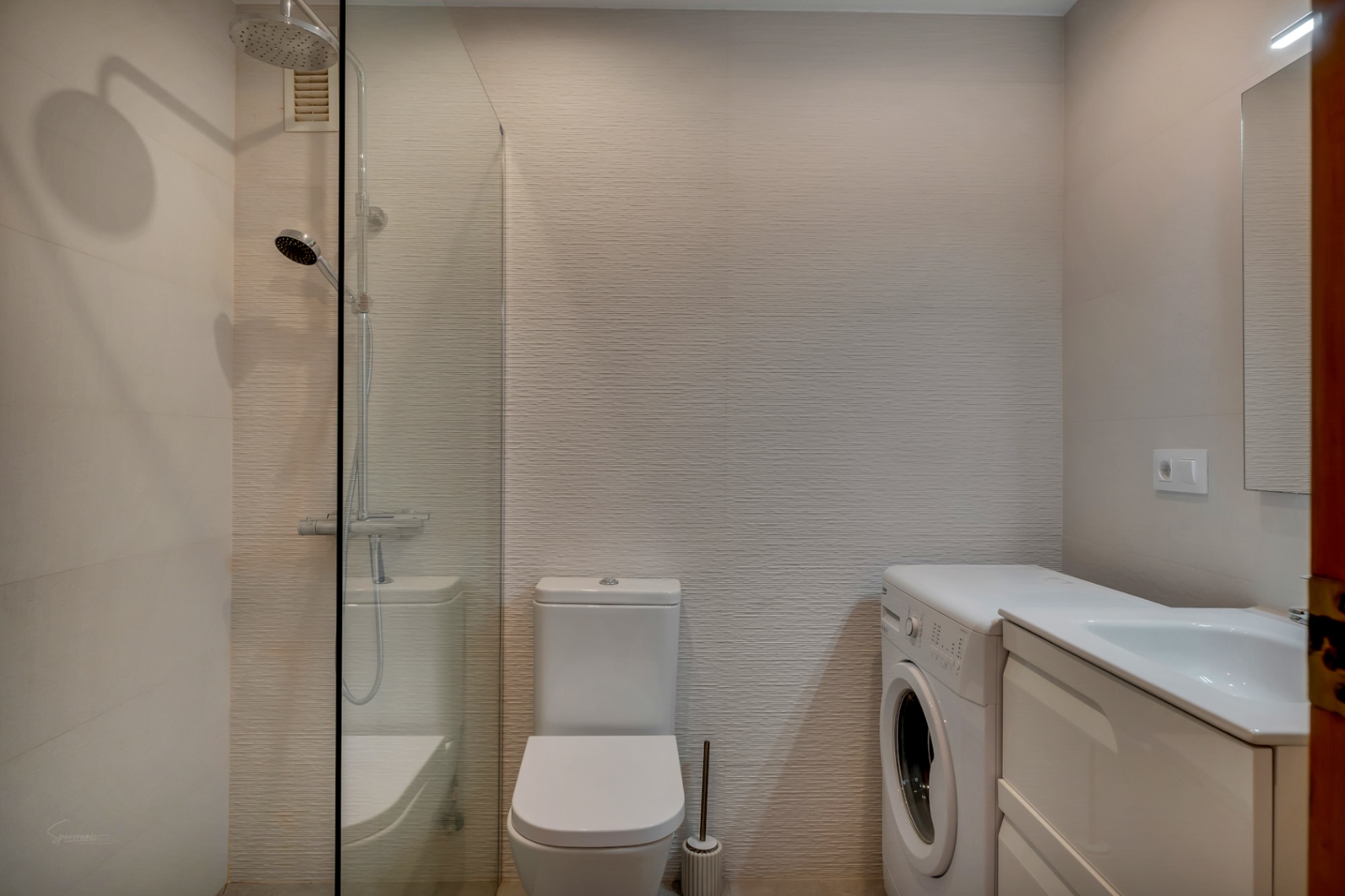 Bathroom featuring a glass shower, white toilet, washing machine, and white vanity with sink.