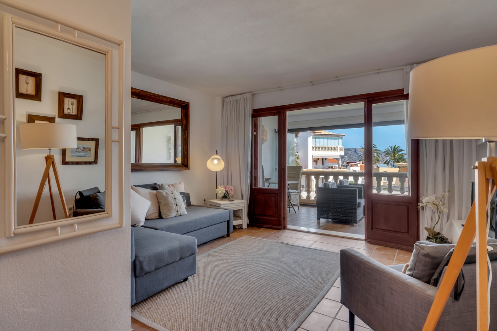Bright living room with glazed terrace and sea views in Jávea. Gray sofa and modern decor.