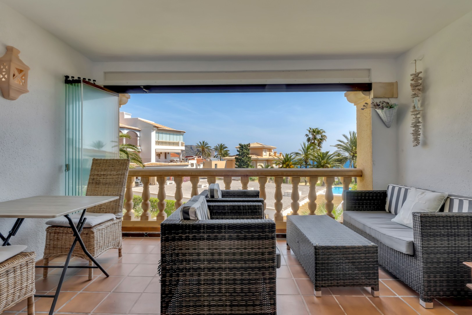 Enclosed terrace featuring wicker furniture and views of the complex and the sea.