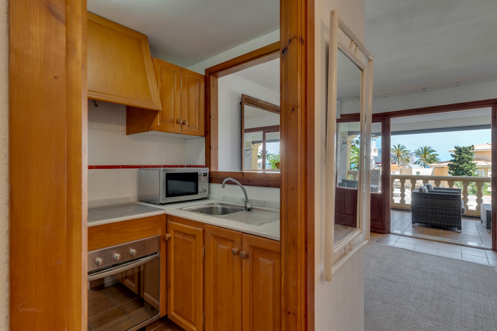 Kitchen with wood cabinets and modern appliances, with a view to the glazed terrace.