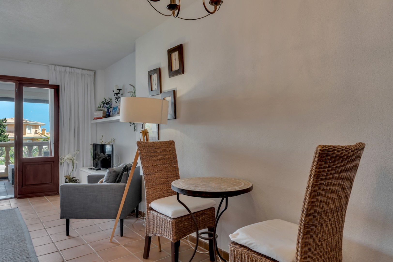 Living room detail with mosaic table and wicker chairs, illuminated by a floor lamp.