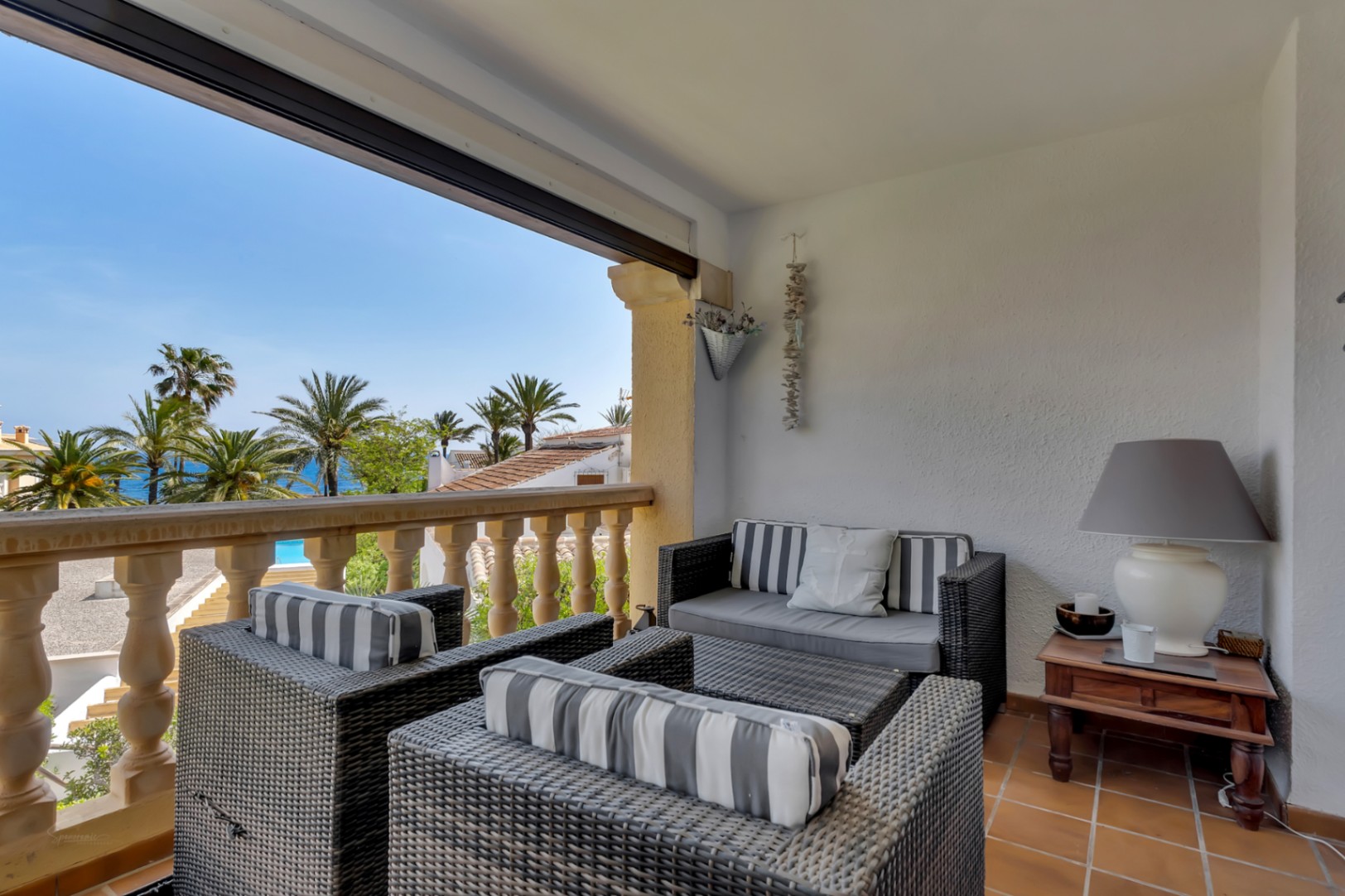 Sea view terrace furnished with wicker armchairs and striped cushions, perfect for relaxation.