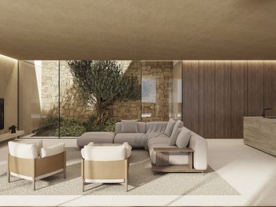 Modern living space with floor-to-ceiling windows showcasing a stone wall and olive tree. Features a modular sofa, armchairs, a stone island with a faucet, and linear ceiling lighting.