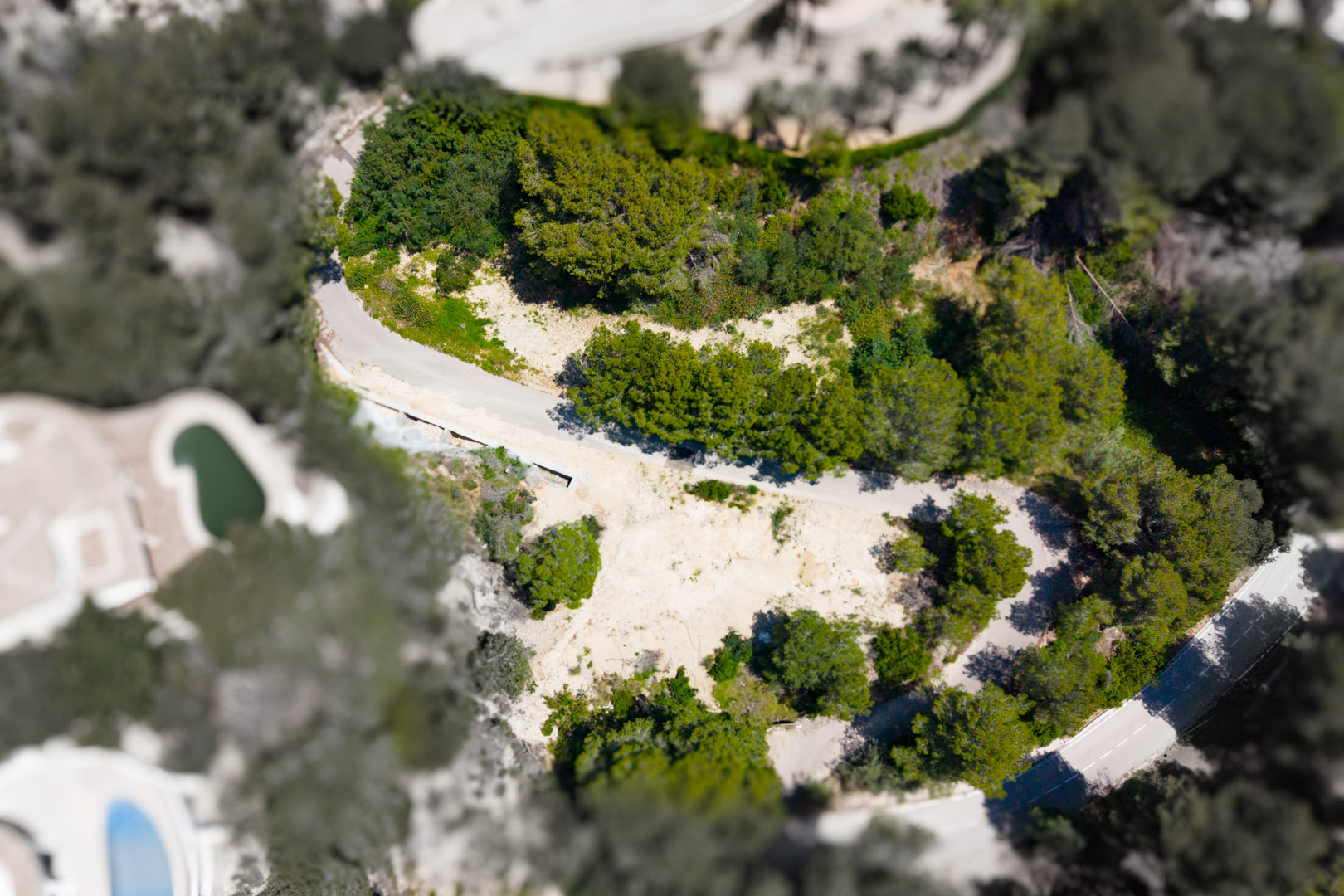 Aerial view of a plot in Mar Azul, Jávea, showcasing undeveloped land surrounded by greenery.