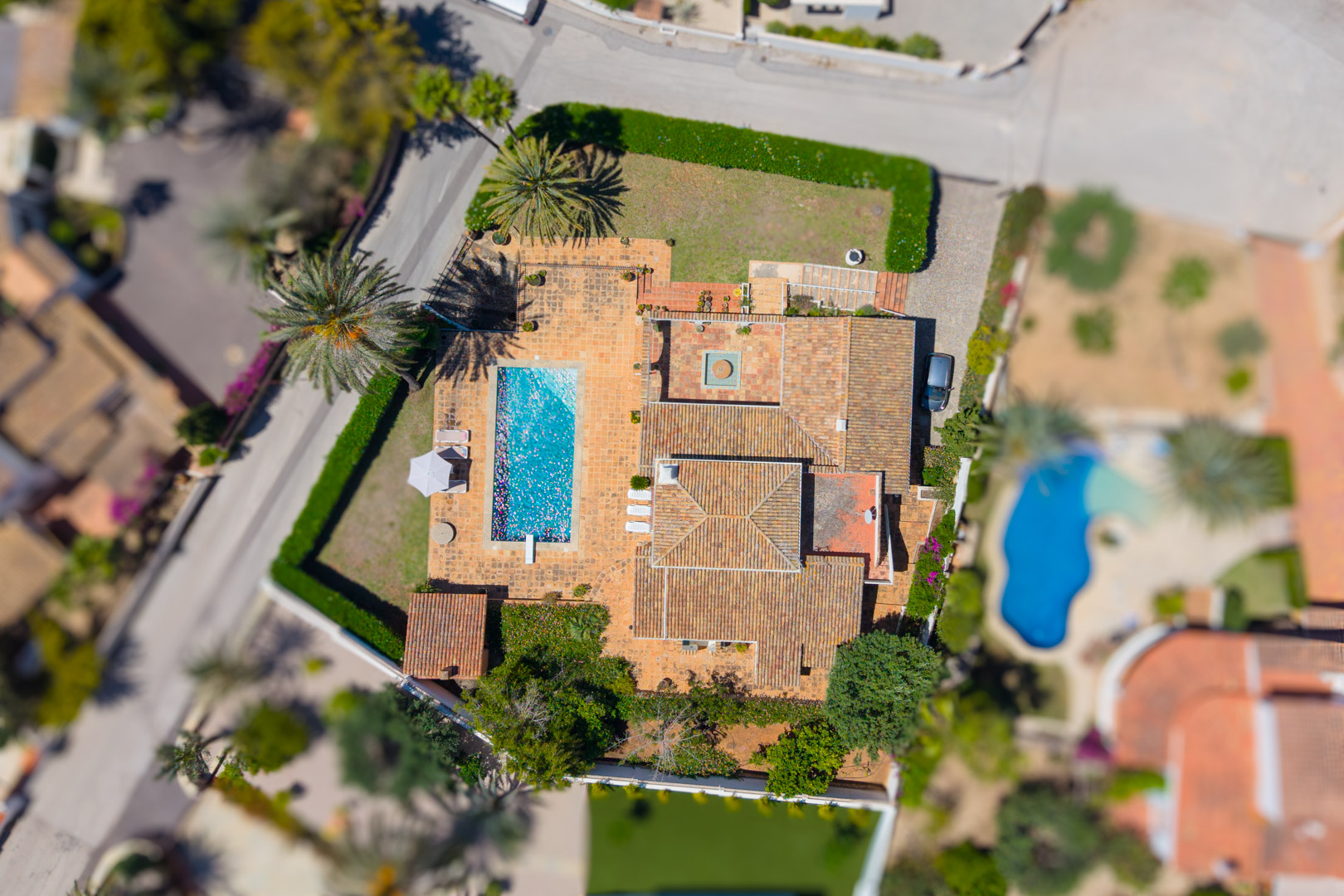 Aerial view of the villa featuring a rectangular pool and red tile roof.