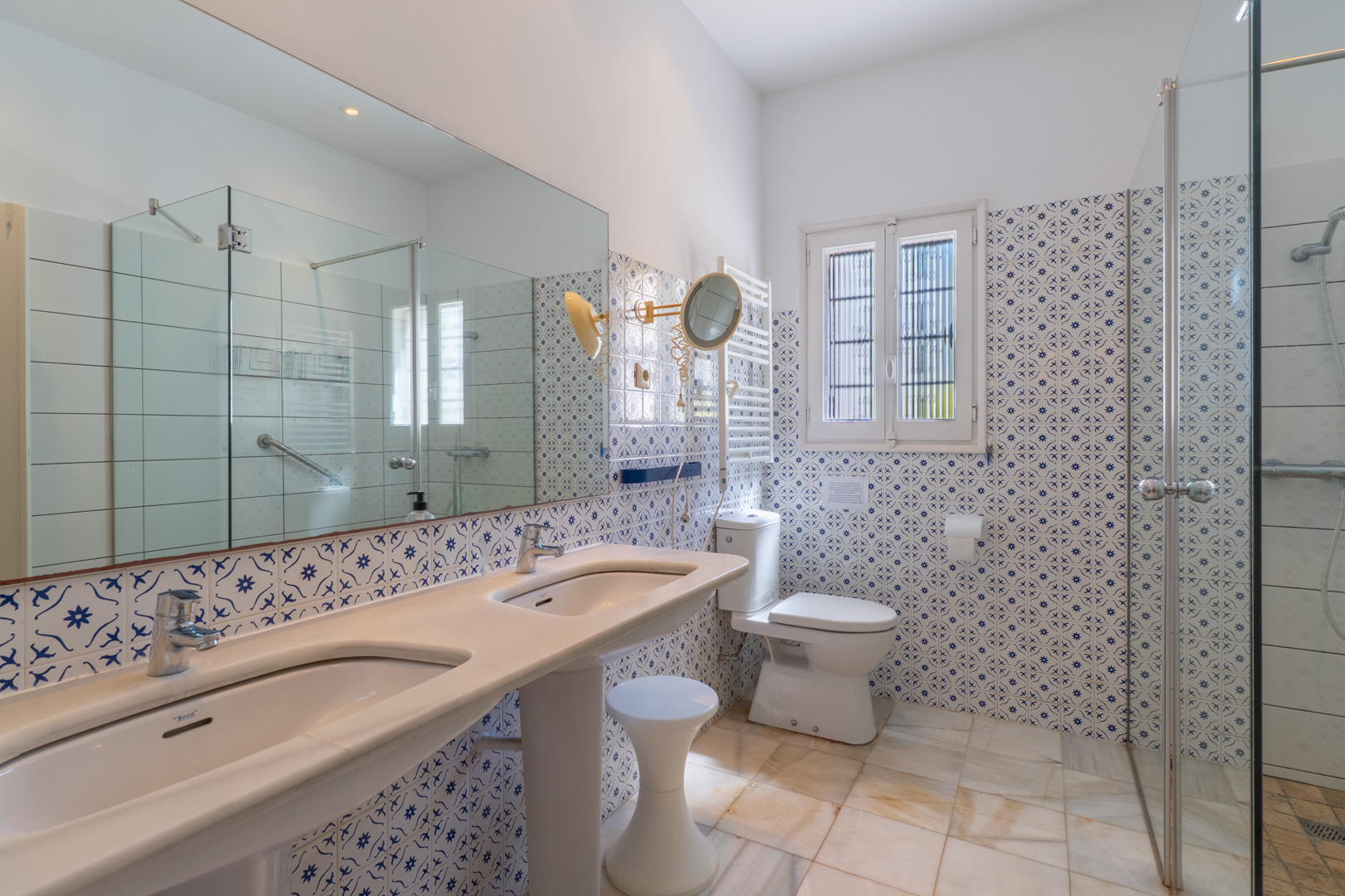Bathroom featuring a double pedestal sink, decorative tile, and glass-enclosed shower.