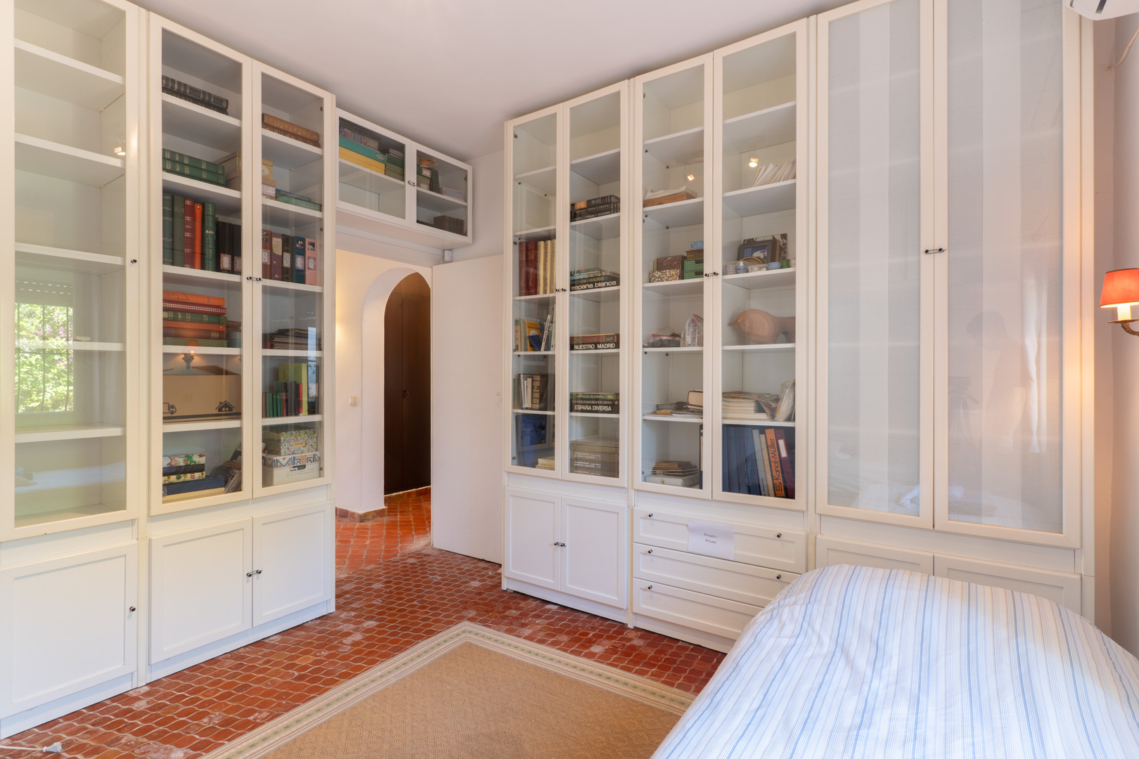 Bedroom featuring built-in white shelving units and terracotta tile flooring.