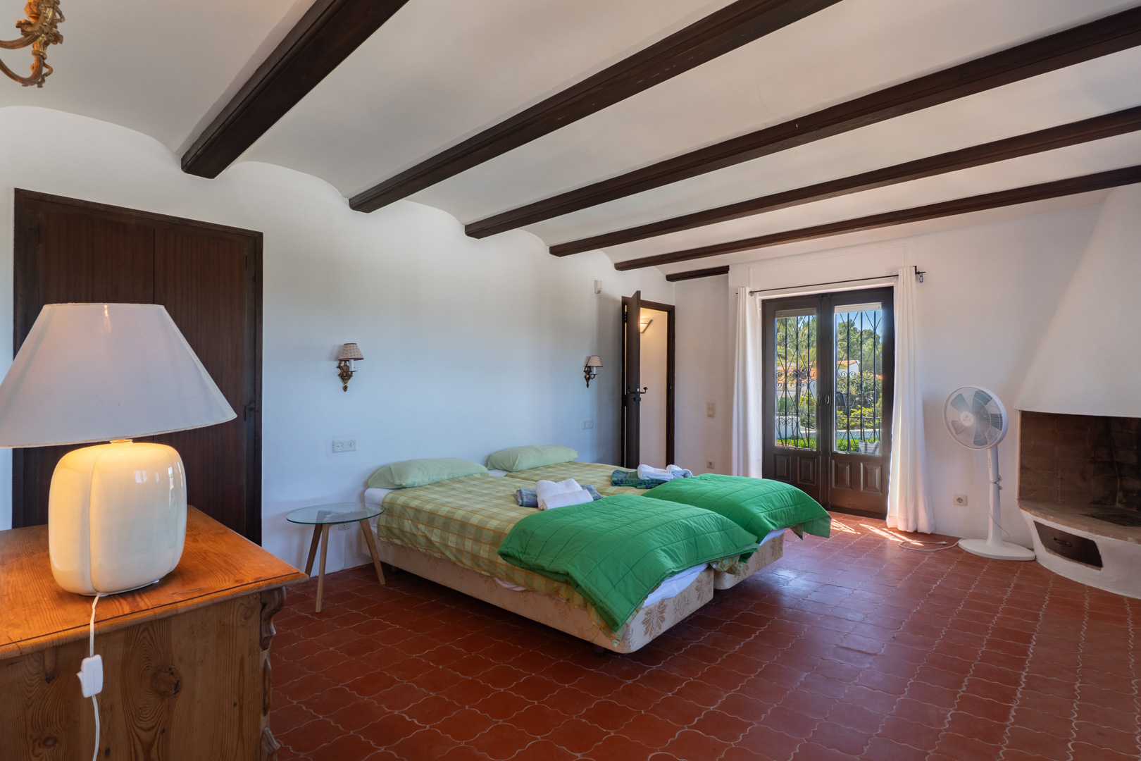 Bedroom with twin beds, wood beams, and terracotta tile flooring.
