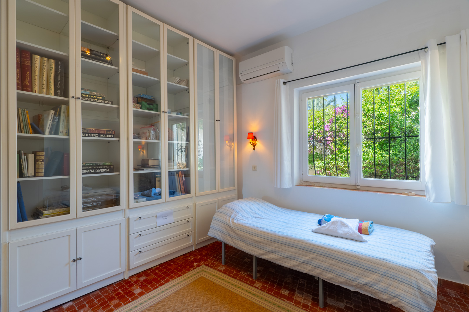 Bright bedroom with built-in shelving and garden view.