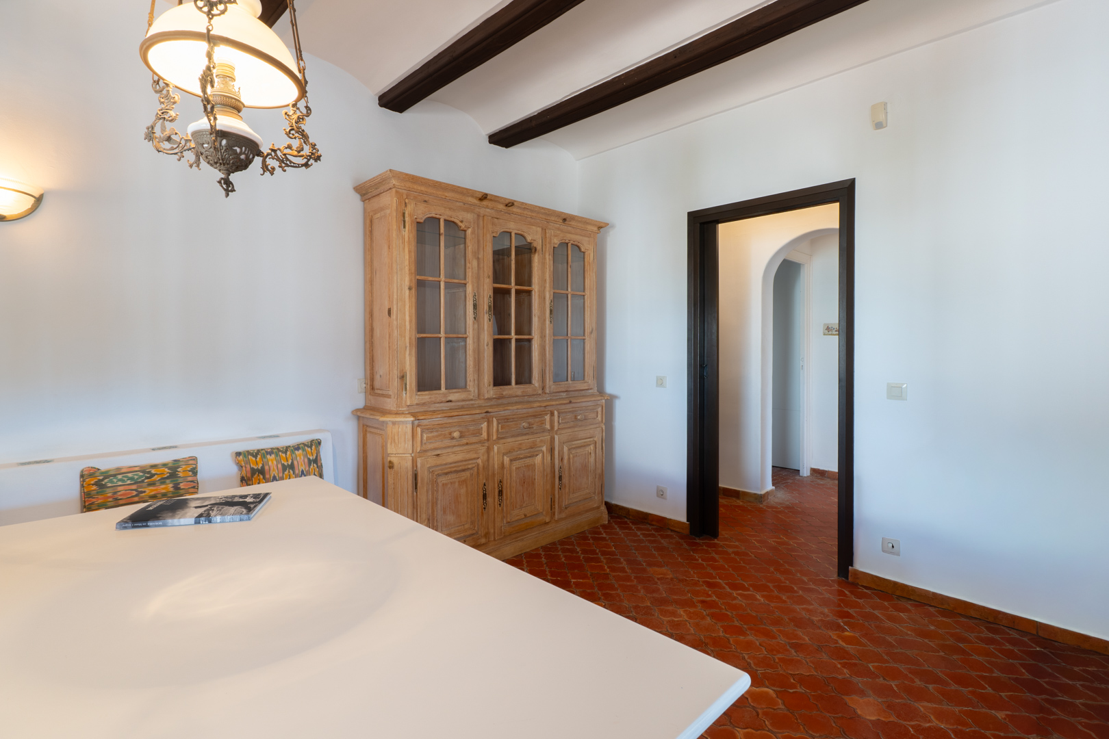 Dining room detail with light wood hutch and terracotta tile flooring.