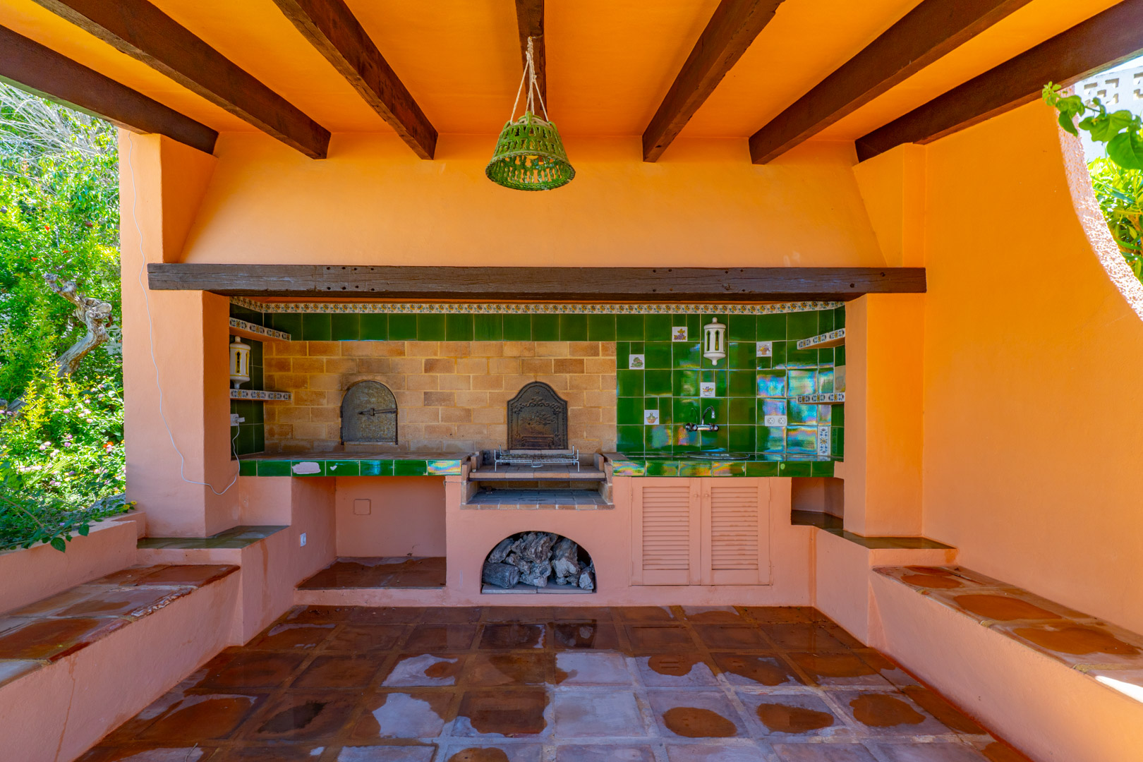 Outdoor barbecue area with terracotta tiled floor, wood-fired oven and sink.