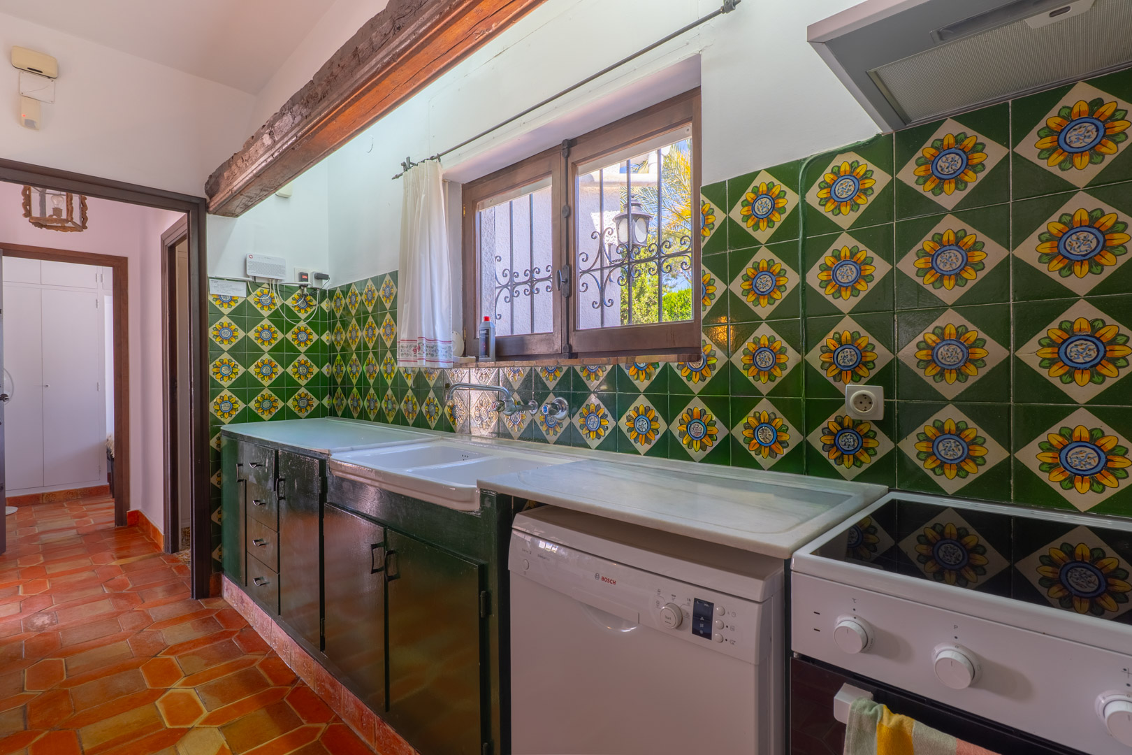 Rustic kitchen featuring decorative tiles, marble countertop, and terracotta flooring.