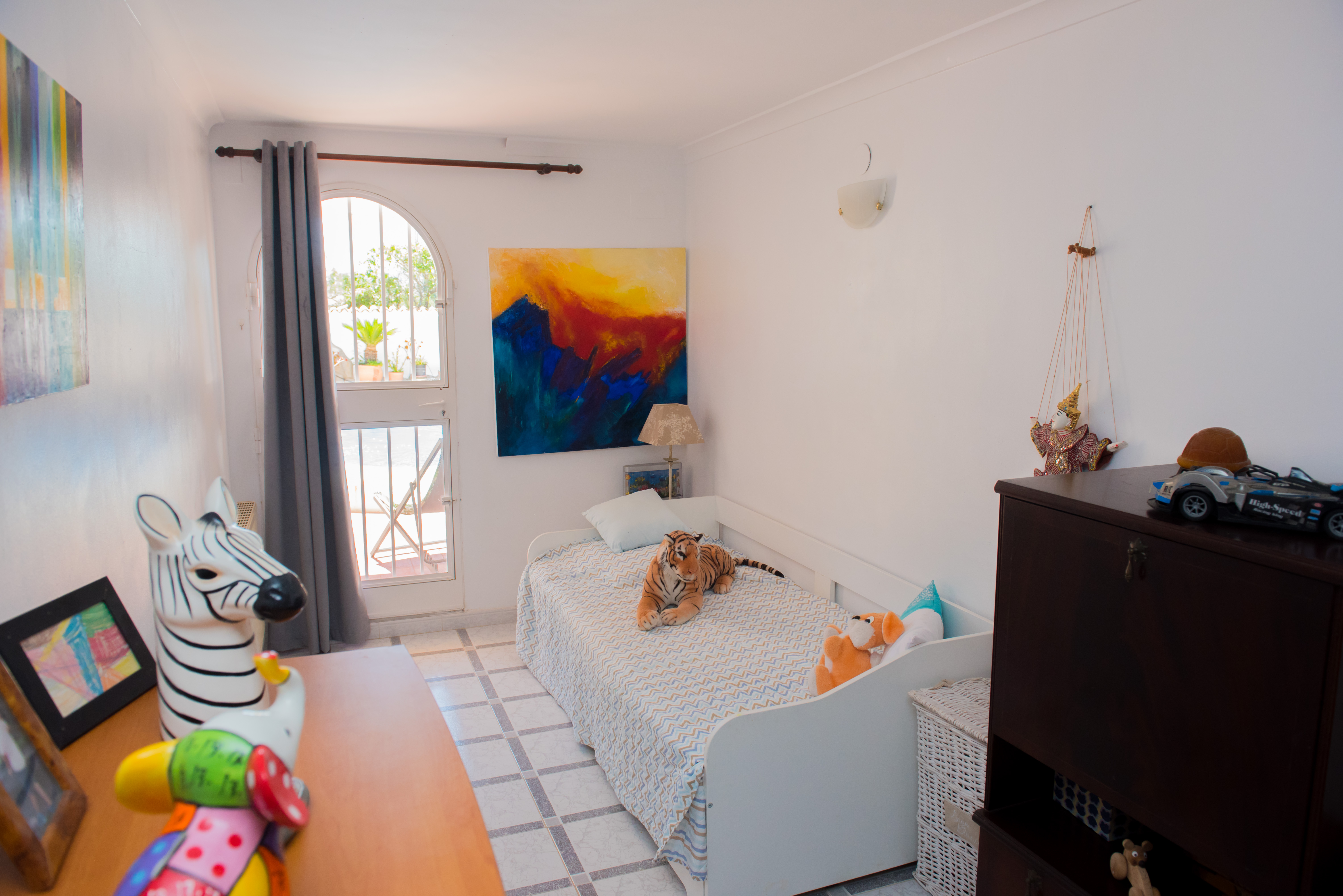 Bright bedroom featuring a twin bed, colorful decor, and outdoor access.