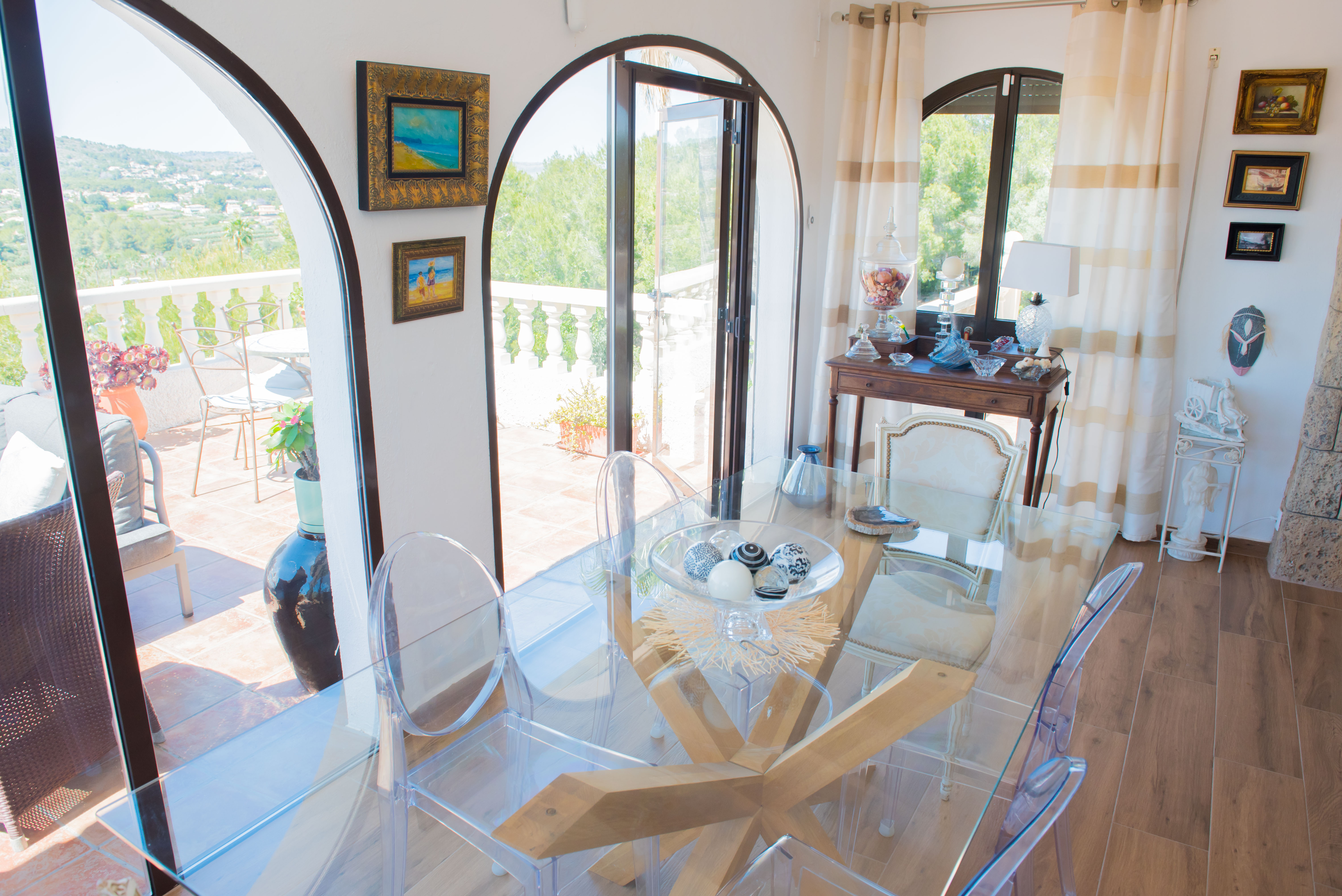 Bright dining room with a glass table and transparent chairs. Terrace views.