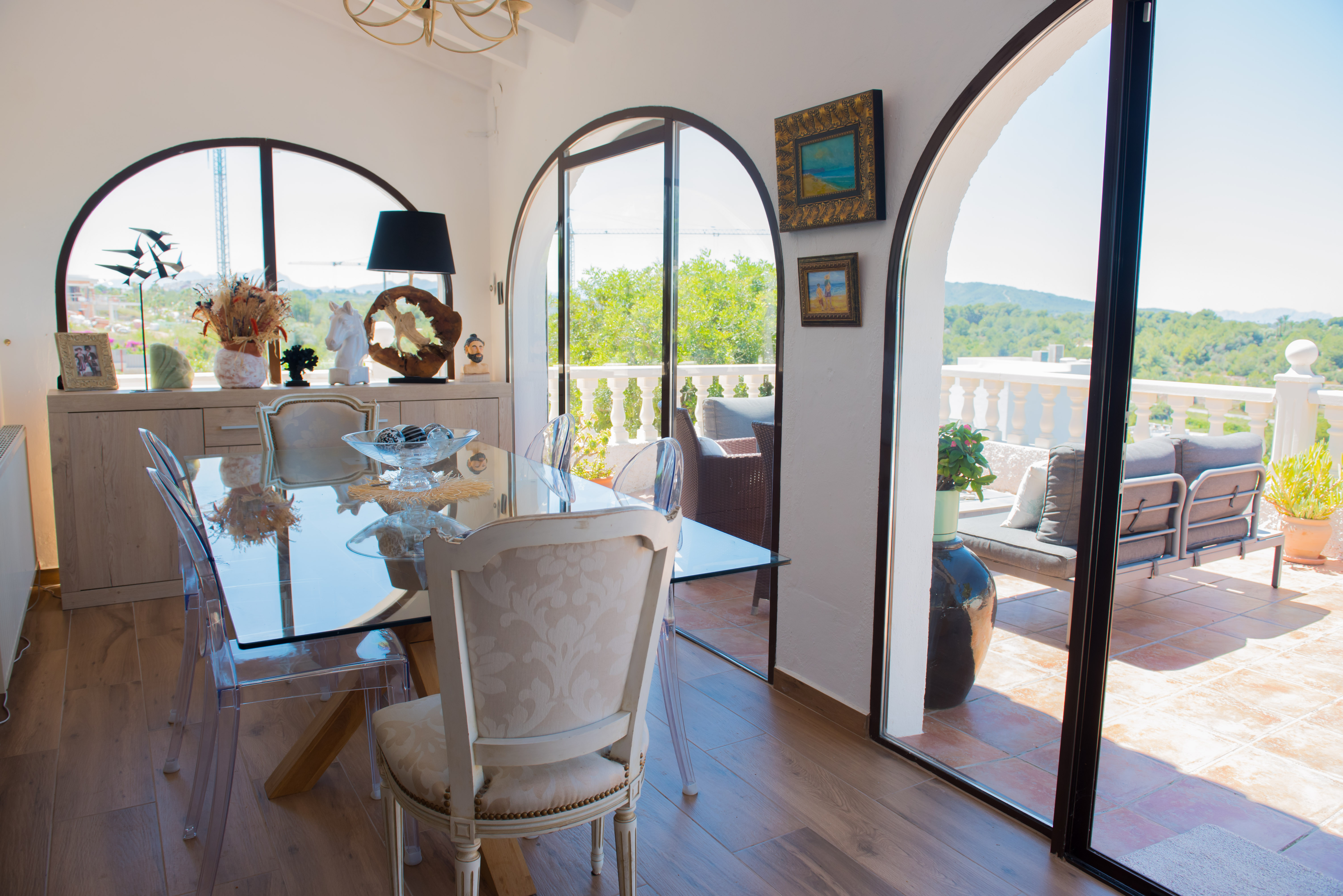 Bright dining room with glass table and access to a terrace with wooded views.