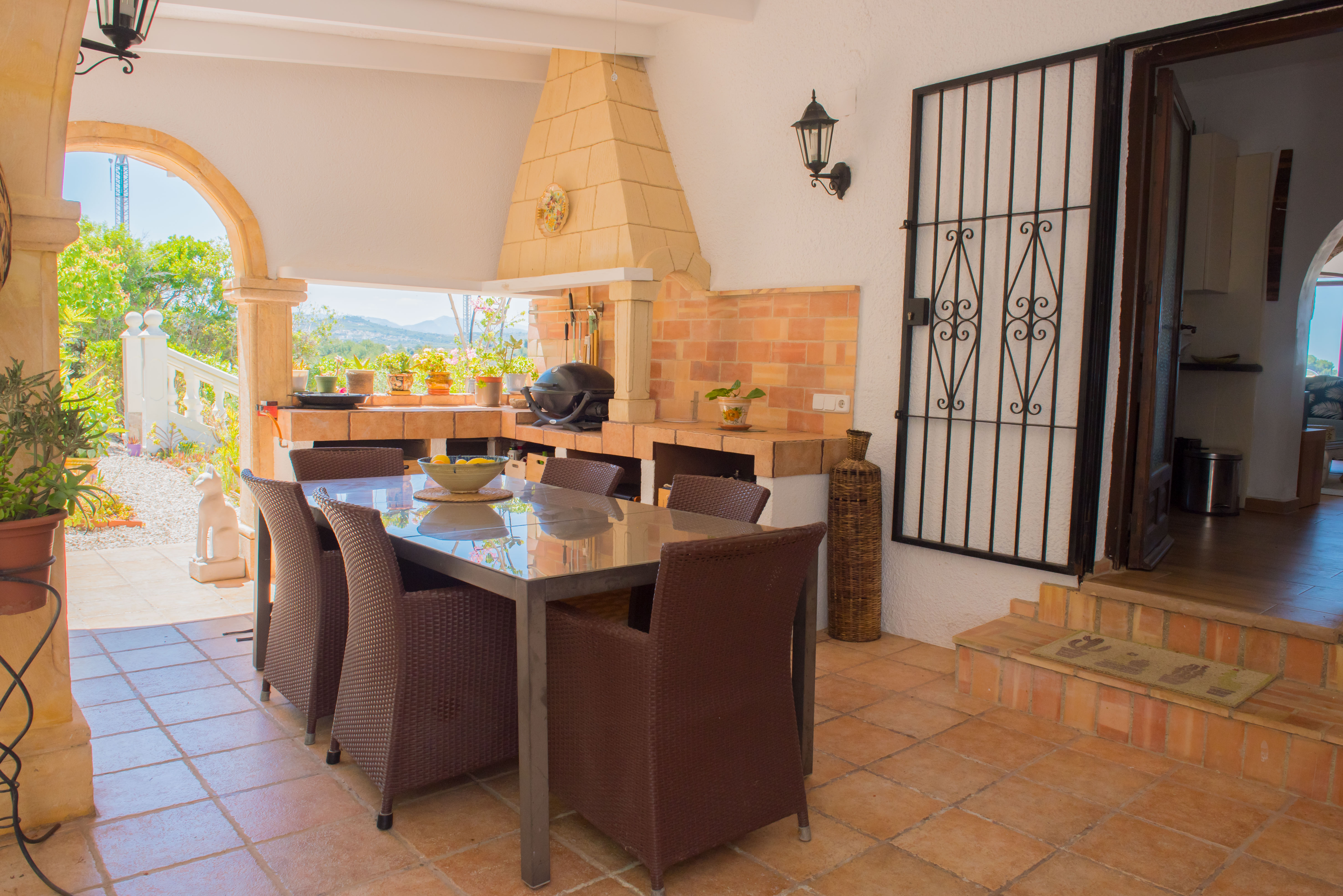 Covered outdoor dining area with brick barbecue and stainless steel table.
