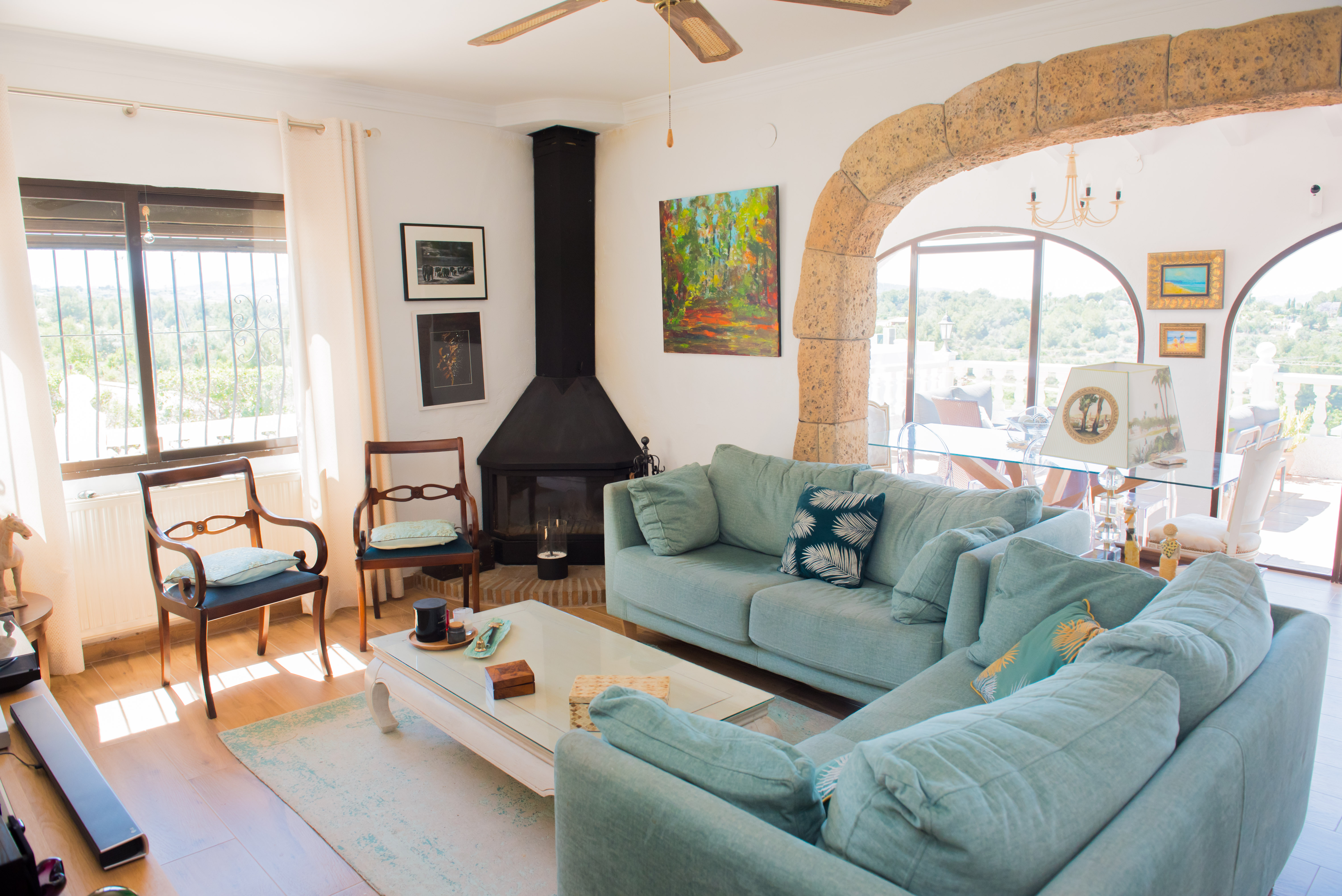 Living room featuring a black fireplace, blue sofa, and stone arch connecting to the outdoor dining area.