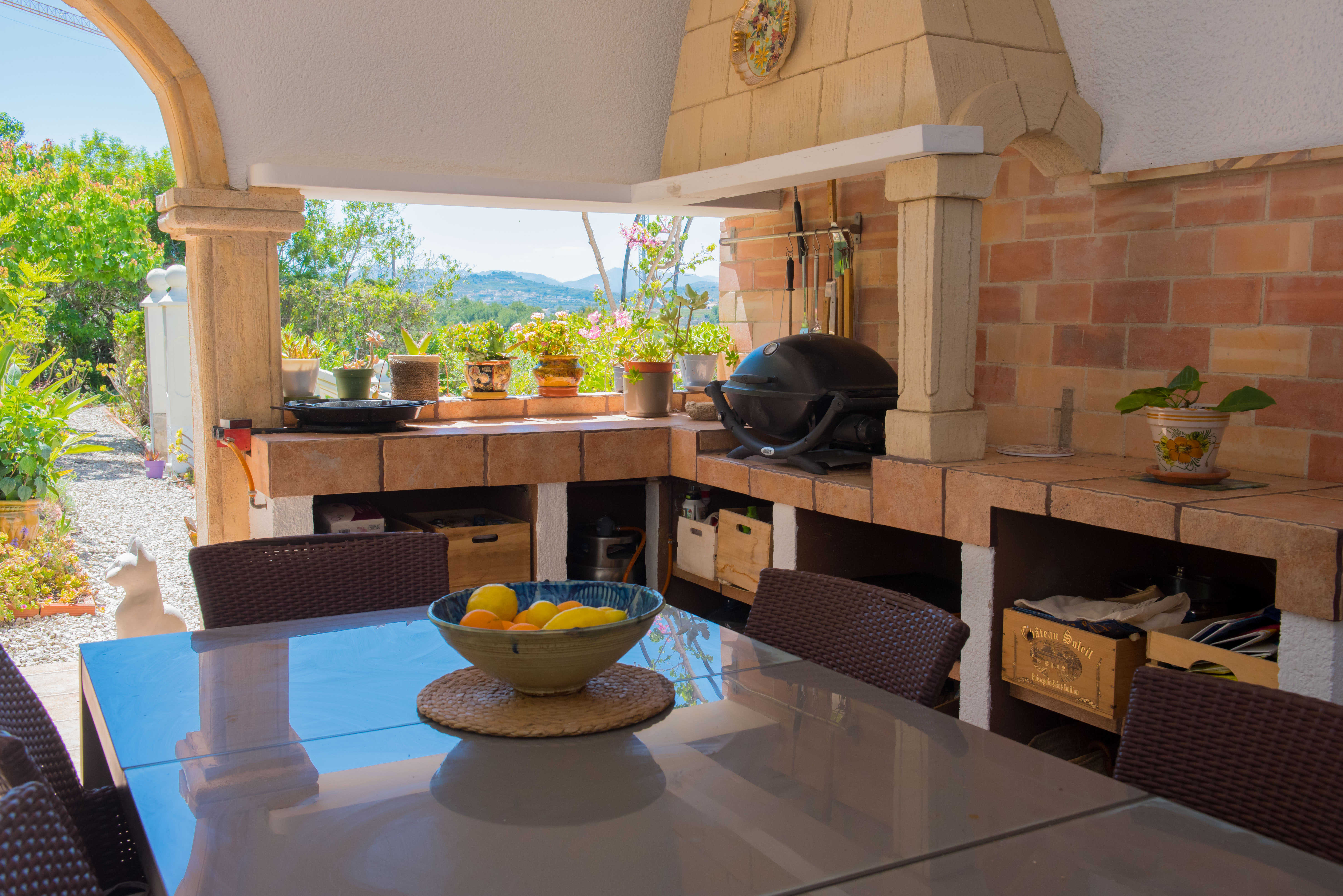 Outdoor BBQ area with brick oven and dining table overlooking the garden.
