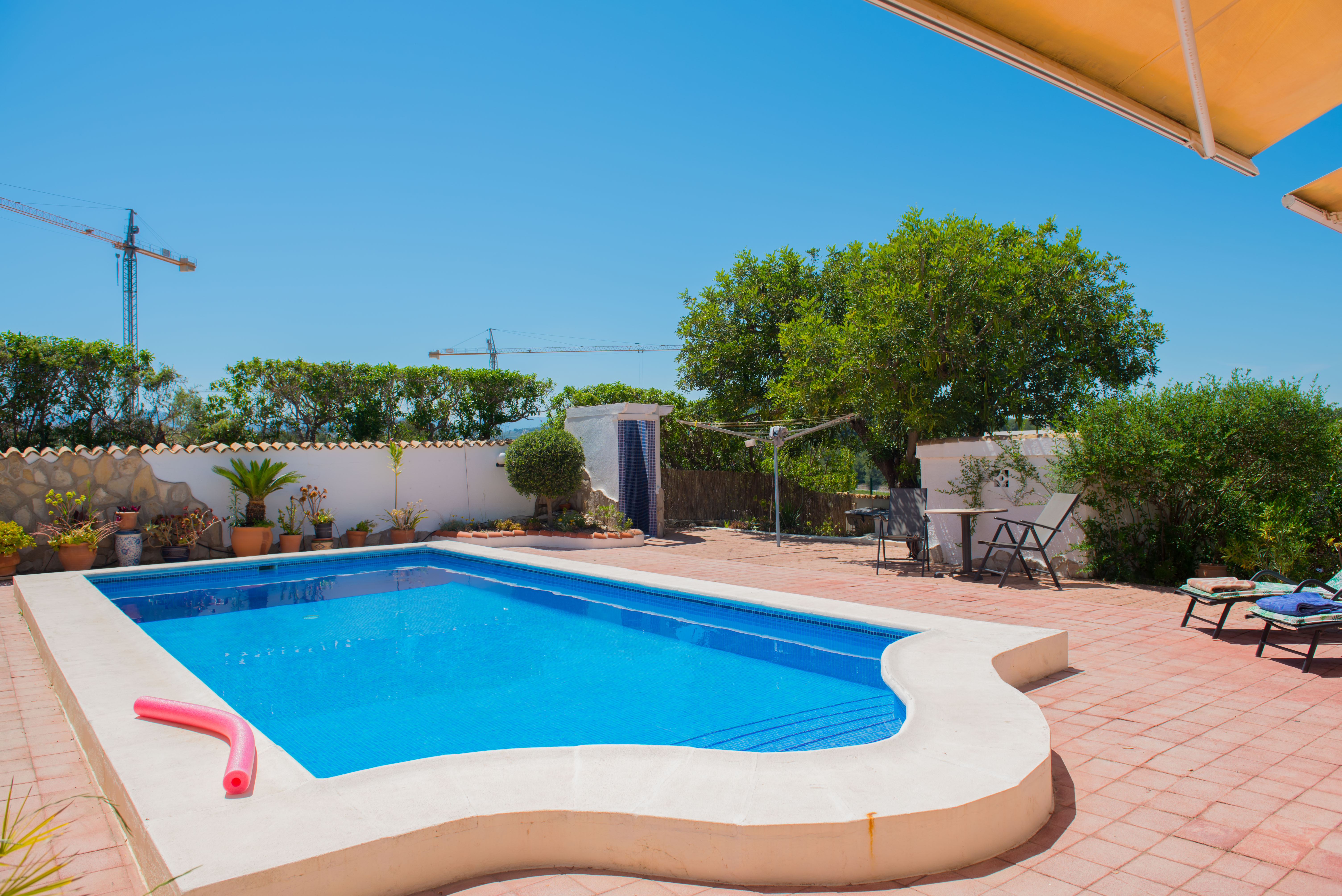 Pool with blue mosaic tiles and white cement border on a red-tiled patio.