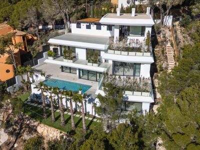 Aerial view of a modern multi-level white villa nestled into a green hillside. Features a large private swimming pool, extensive terraces with glass railings, and palm trees, surrounded by Mediterranean forest.