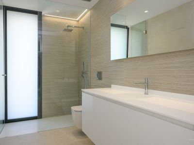 Contemporary bathroom featuring a double white floating vanity, a walk-in shower with textured wall tiles, and a frosted glass door, complemented by modern chrome fixtures and integrated lighting.