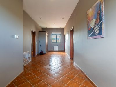 Corridor featuring terracotta tiled floors, grey walls, and dark wood doors. A window at the end provides mountain views above a radiator.