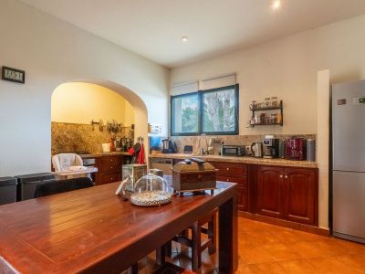 Equipped kitchen featuring granite countertops, dark wood cabinetry, terracotta floor tiles, and a central wooden dining table. An archway connects to an additional preparation area.