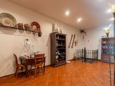 Functional home office area featuring a wooden desk, terracotta floor tiles, and traditional wall decor. The space includes a bookshelf and an elegant wrought-iron balustrade.