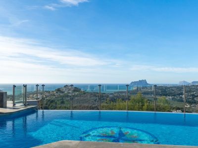 The infinity pool, featuring a distinctive central mosaic, visually merges with the horizon. It offers panoramic sea views, the coastline, and the iconic Peñón de Ifach.