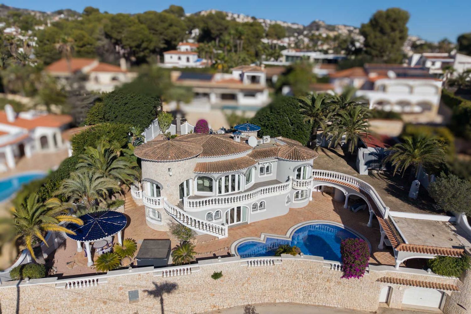 Aerial view of the luxury villa showcasing its distinctive architecture, private pool, multiple terraces with white balustrades, and lush Mediterranean garden.