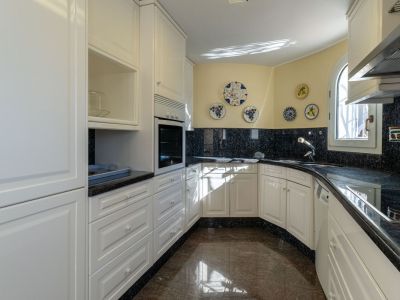 Independent kitchen featuring white paneled cabinets, dark granite countertops and backsplash. It includes a built-in oven, sink, and an arched window providing natural light.