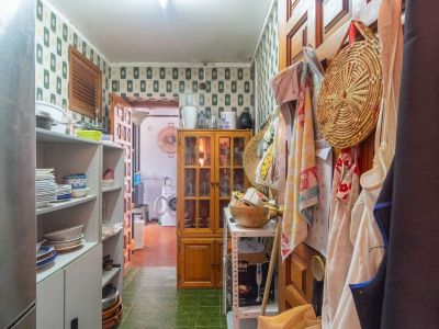 Functional utility area featuring patterned wallpaper, green tiled floor, open shelving with kitchenware, and a wooden display cabinet. A laundry zone is visible beyond.