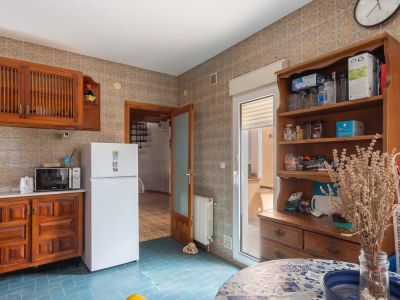 Kitchen featuring blue tiled flooring and patterned wall tiles. Equipped with wooden cabinetry, a refrigerator, and direct access to an outdoor terrace.