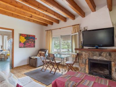 Living area featuring a stone fireplace with a TV, complemented by a wooden beamed ceiling and natural light from the window.