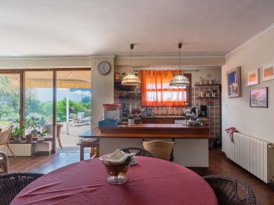 Open-plan living and dining area featuring an integrated kitchen with a wooden breakfast bar and direct access to the outdoor terrace via large glass sliding doors.