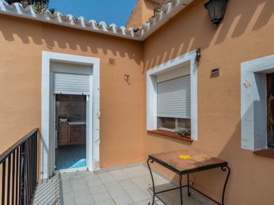 Outdoor terrace featuring light tiled flooring, terracotta-colored walls, and direct access to the kitchen. Includes a wrought-iron table and black railing.