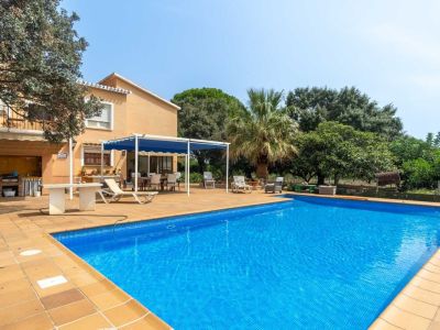 Spacious blue mosaic pool surrounded by a tiled sun terrace, featuring a shaded outdoor dining area and a built-in barbecue zone.