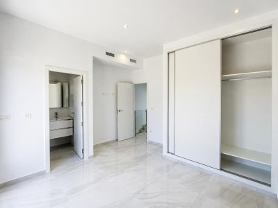 Bright bedroom featuring light porcelain tile flooring and a built-in sliding door wardrobe. Direct access to an en-suite bathroom and ducted air conditioning.
