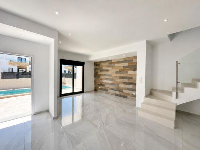 Spacious living area featuring polished porcelain tiles, a decorative wood-effect panel wall, and direct access to the private pool. Modern staircase with glass railing.