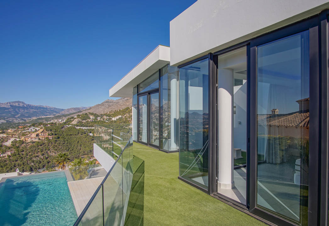 The spacious, light-filled living area features a contemporary gas fireplace and expansive floor-to-ceiling windows, framing breathtaking sea and mountain vistas.