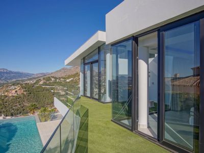 The spacious, light-filled living area features a contemporary gas fireplace and expansive floor-to-ceiling windows, framing breathtaking sea and mountain vistas.