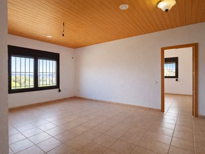 Spacious room featuring light tiled flooring, white textured walls, and a warm wooden slatted ceiling. Windows with security bars provide natural light and valley views.