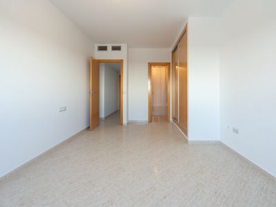Empty room featuring light tiled flooring, a built-in wooden wardrobe with sliding doors, and multiple wooden doors leading to adjacent spaces. Air conditioning vents are visible.