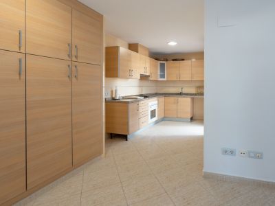 Spacious kitchen featuring light wood cabinetry, speckled granite countertops, and an integrated oven. A large matching pantry unit stands on the left, complementing the beige tiled floor.